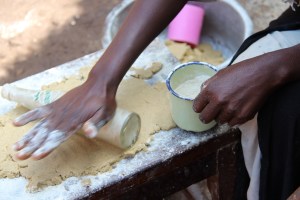 rolling out Cassava flour, bananas, and baking soda to prepare her pancakes for sale.